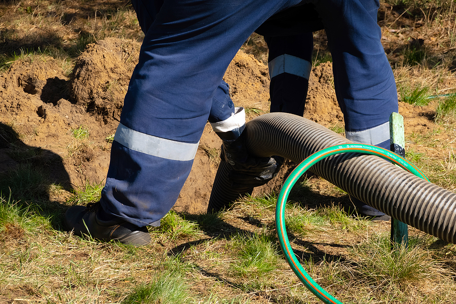 Man worker holding pipe, providing sewer cleaning service outdoor.